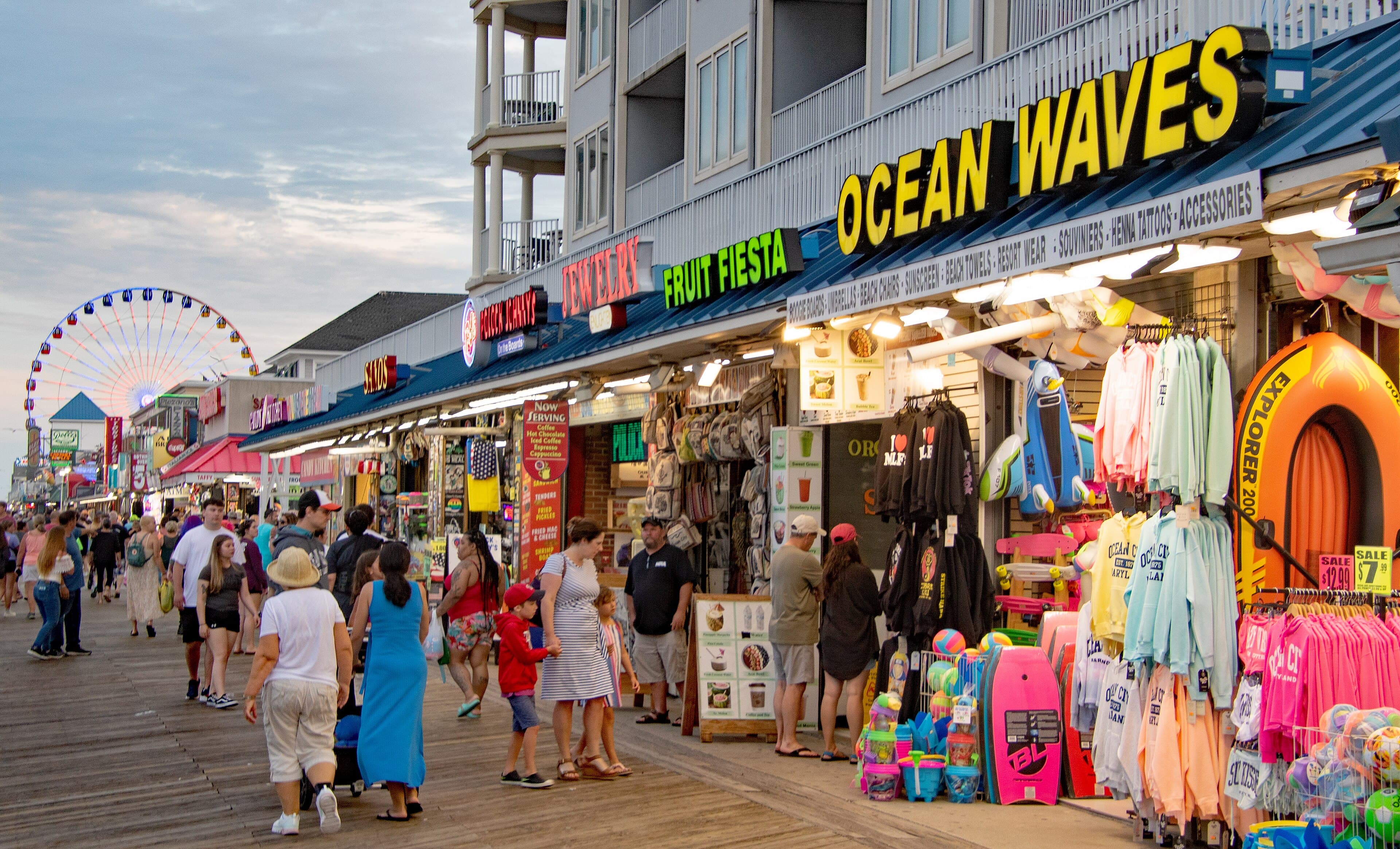 Ocean City's wooden Boardwalk busy with pedestrians beside shops and oceanfront buildings.